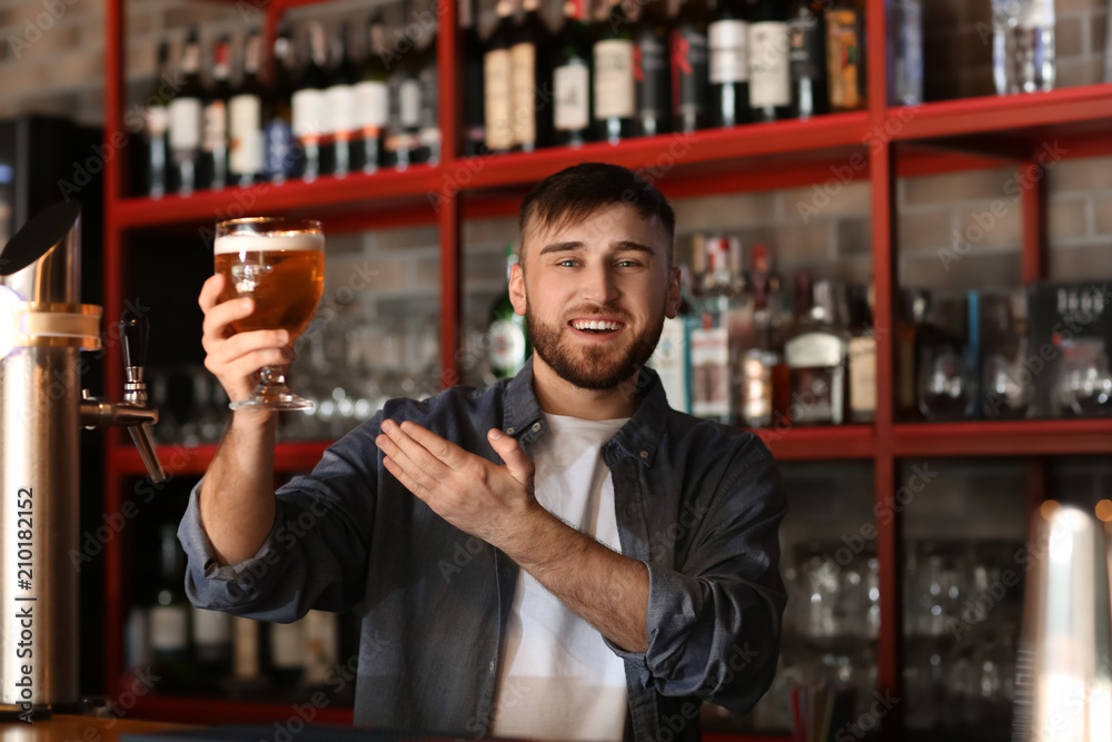 Bartender with glass of beer in bar