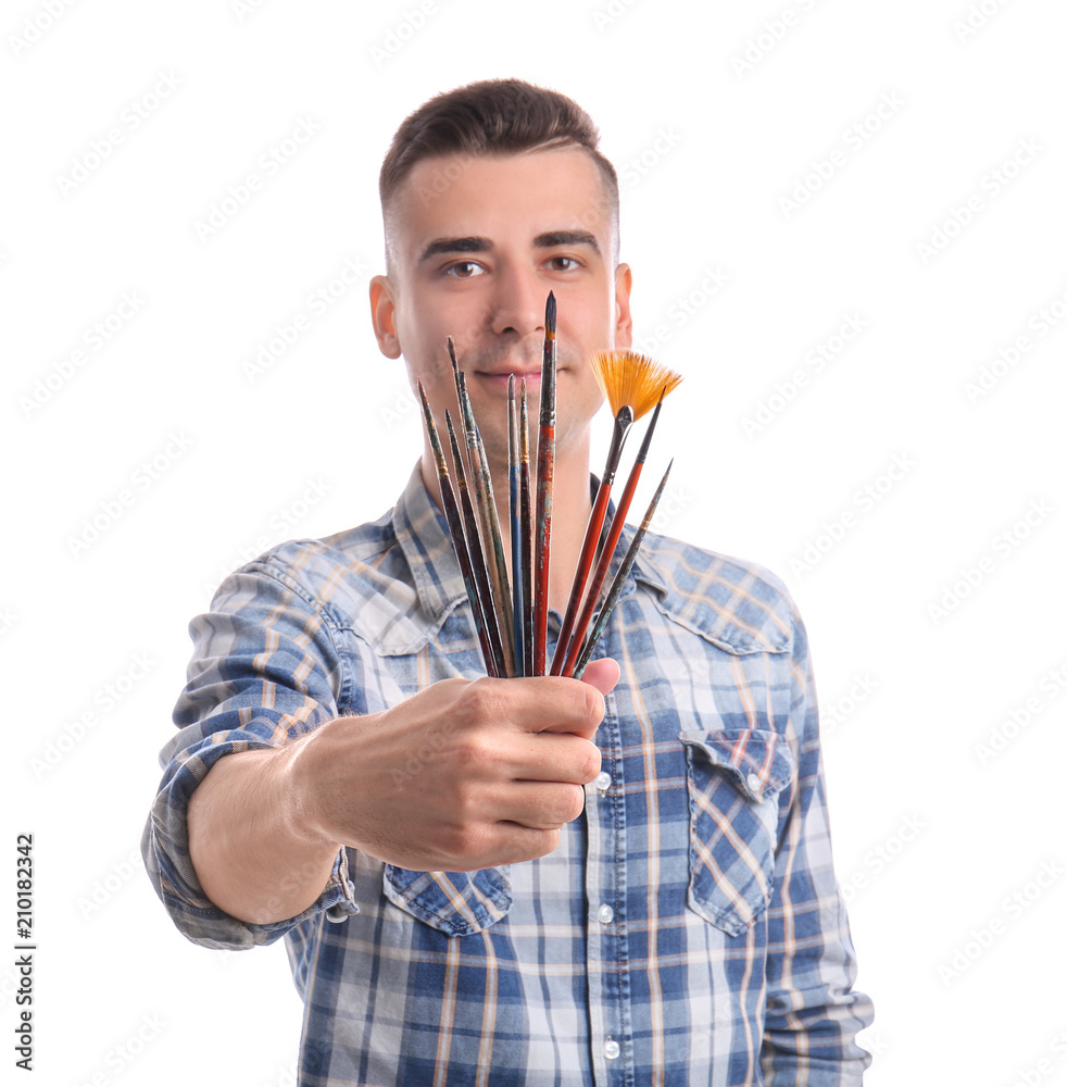 Male artist with paintbrushes on white background