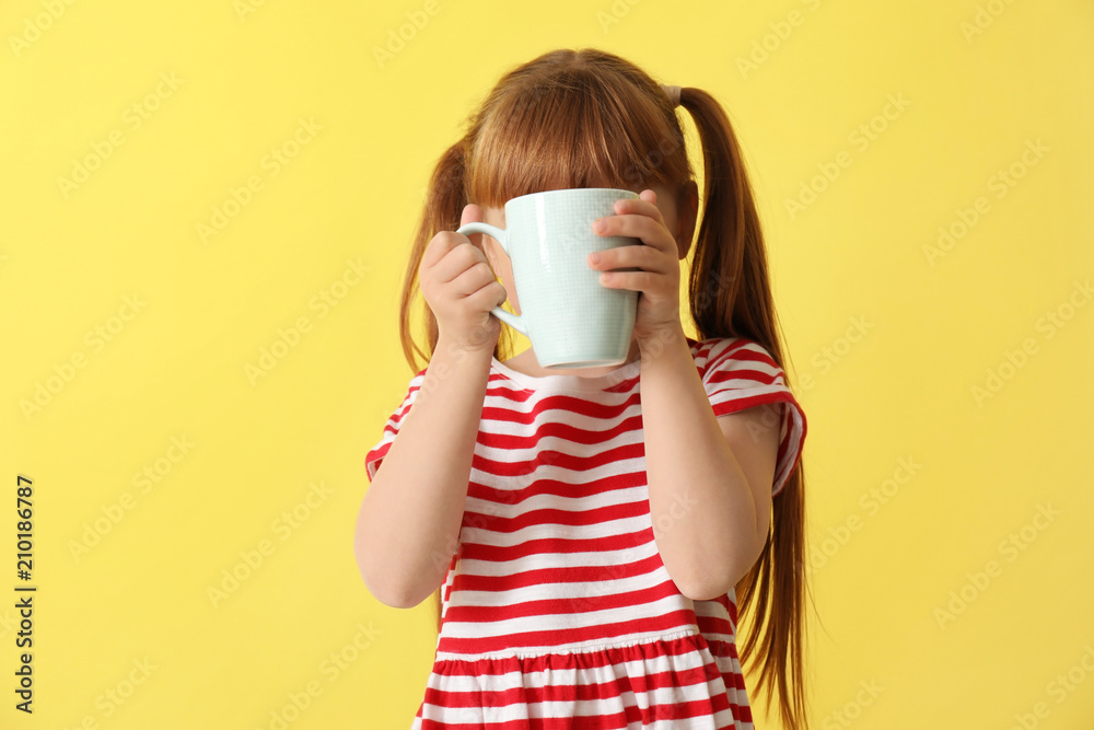 Cute little girl with cup of hot cocoa drink on color background