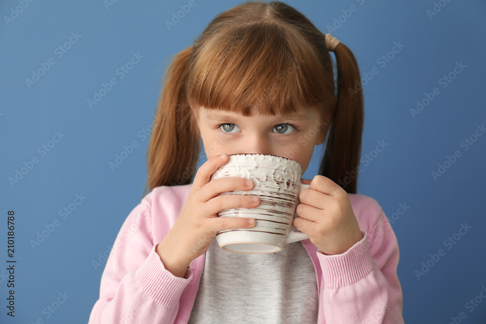 Cute little girl with cup of hot cocoa drink on color background