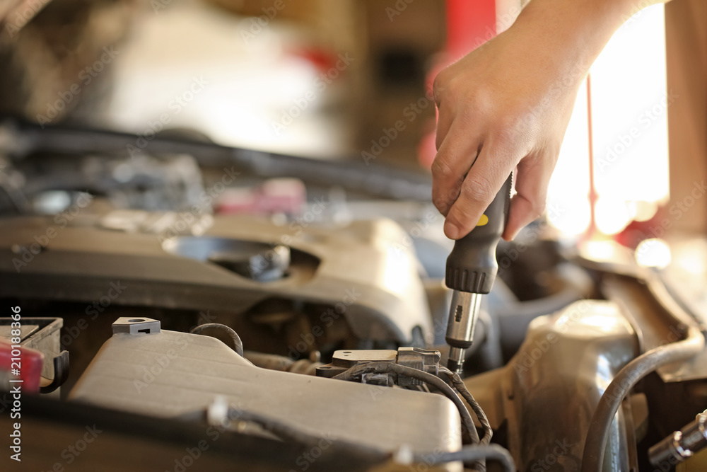 Auto mechanic repairing car in service center, closeup