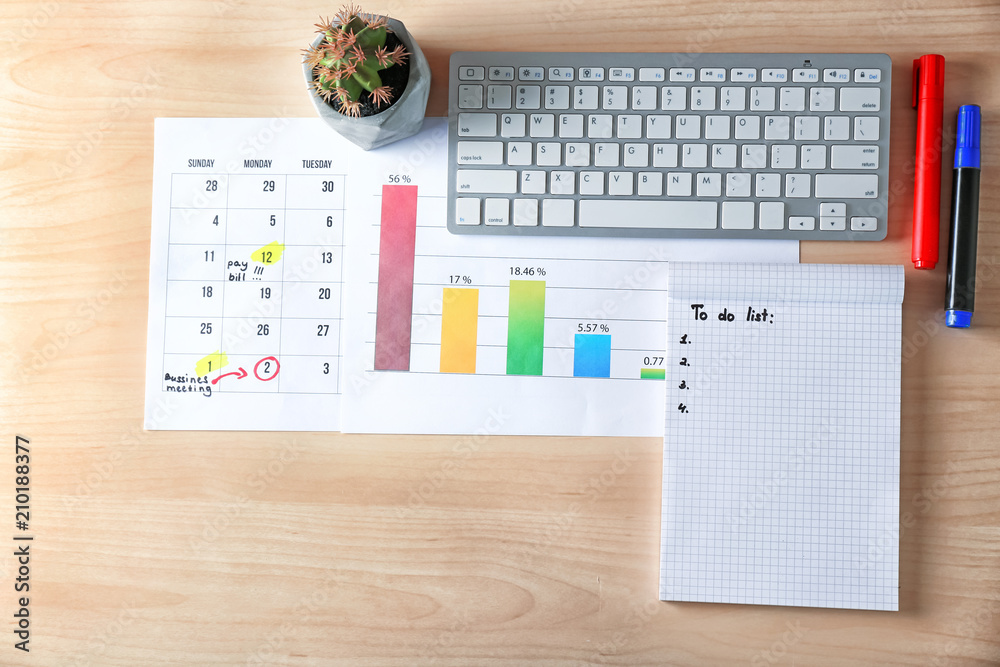 Calendar with to-do list, computer keyboard and chart on wooden background