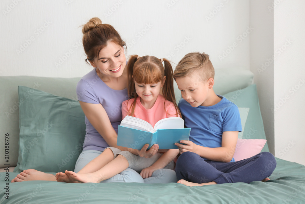 Mother and her children reading book together at home