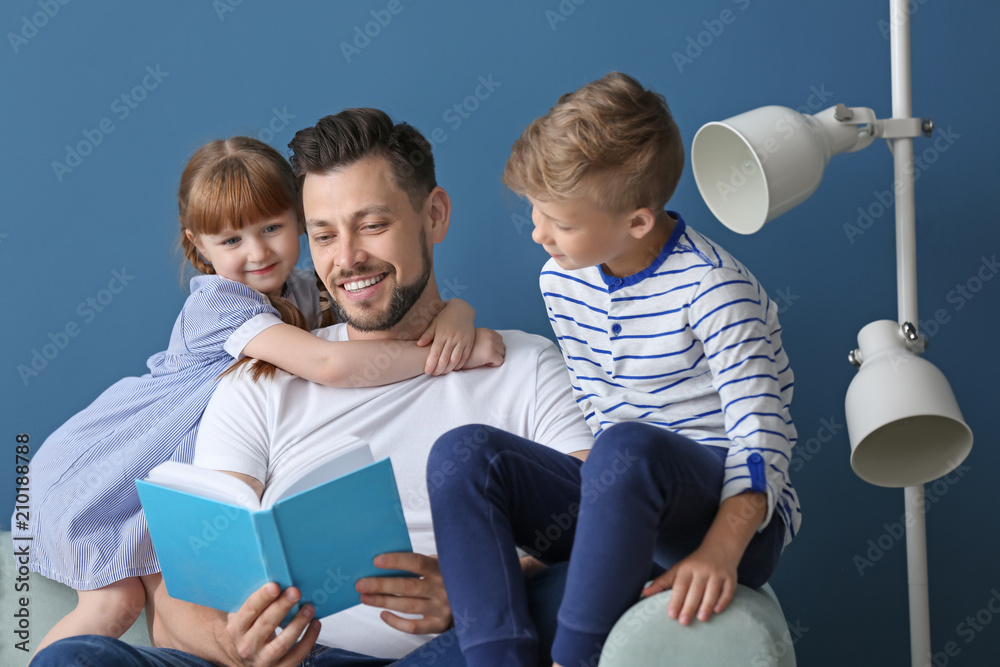 Father and his children reading book together at home