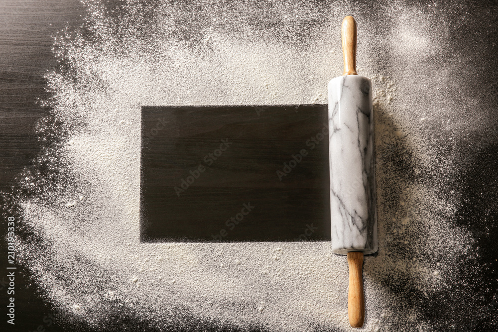 Frame made of flour and rolling pin on dark background