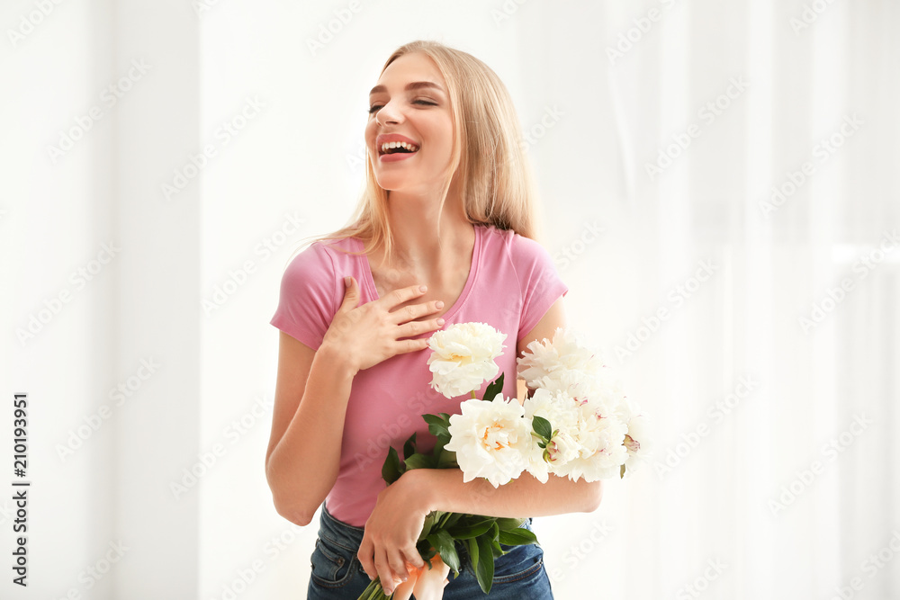 Attractive young woman with beautiful flowers near window