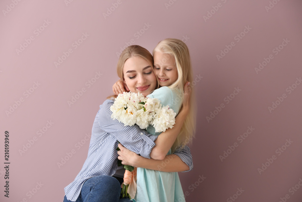 Attractive young woman and cute little girl with beautiful flowers on color background