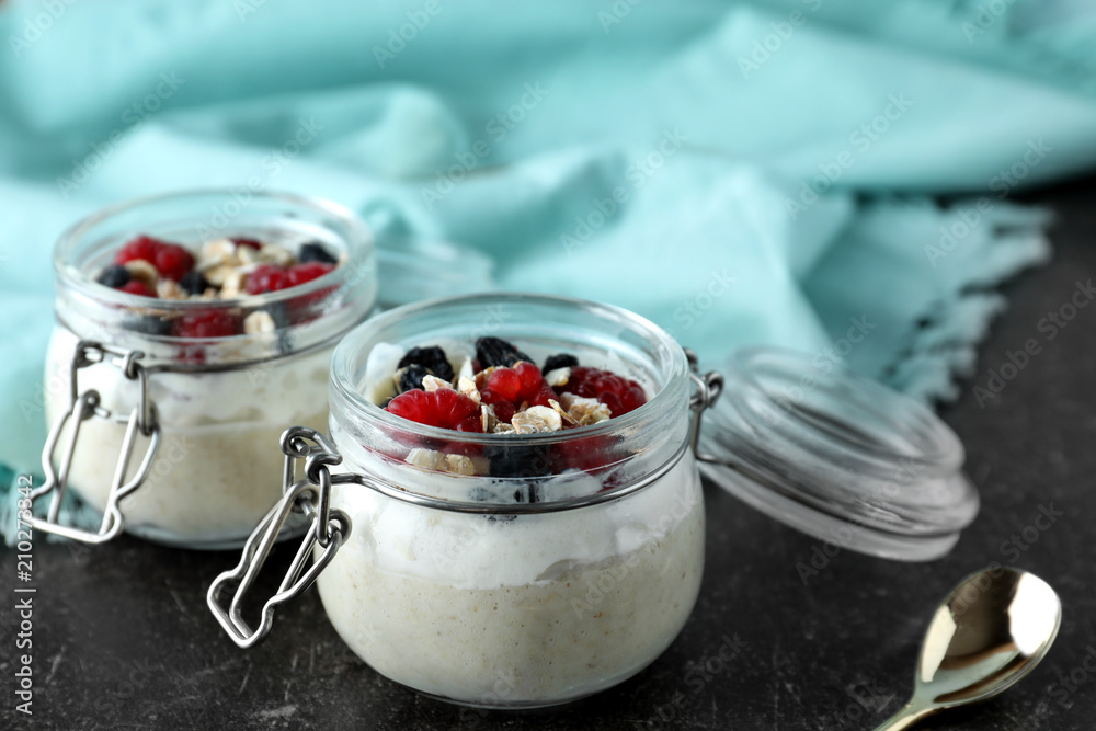 Tasty oatmeal dessert with fresh berries in glass jars on table