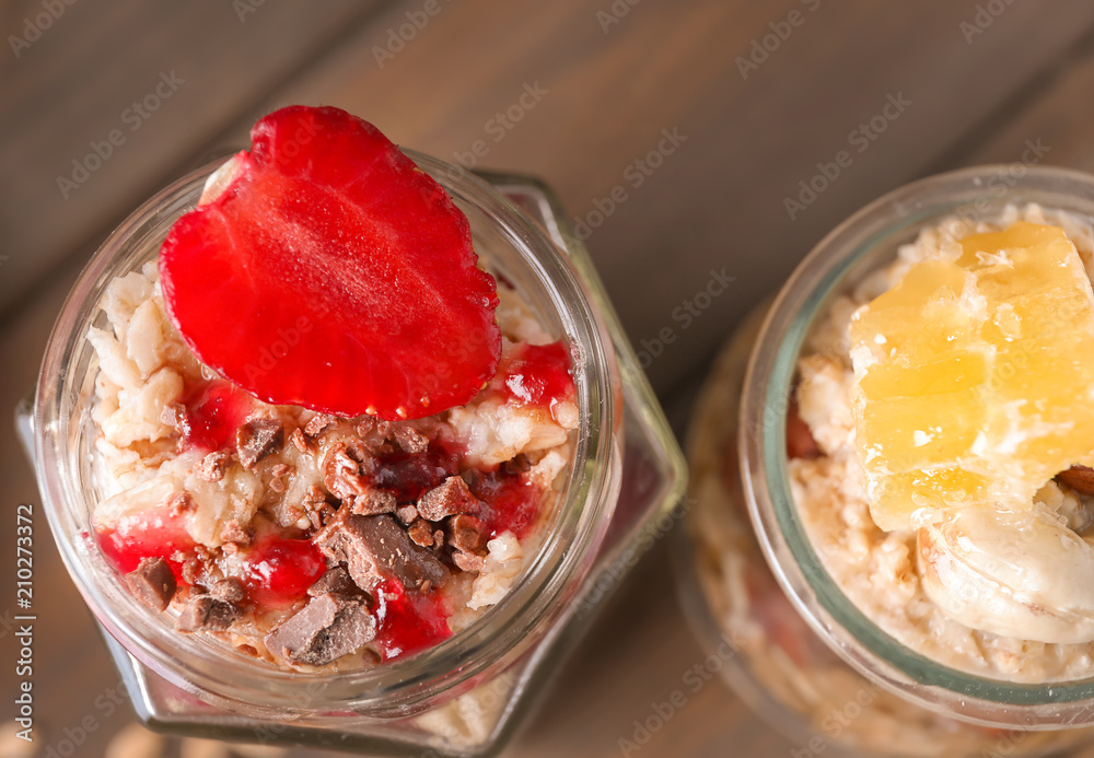 Tasty oatmeal desserts in glass jars on table, closeup