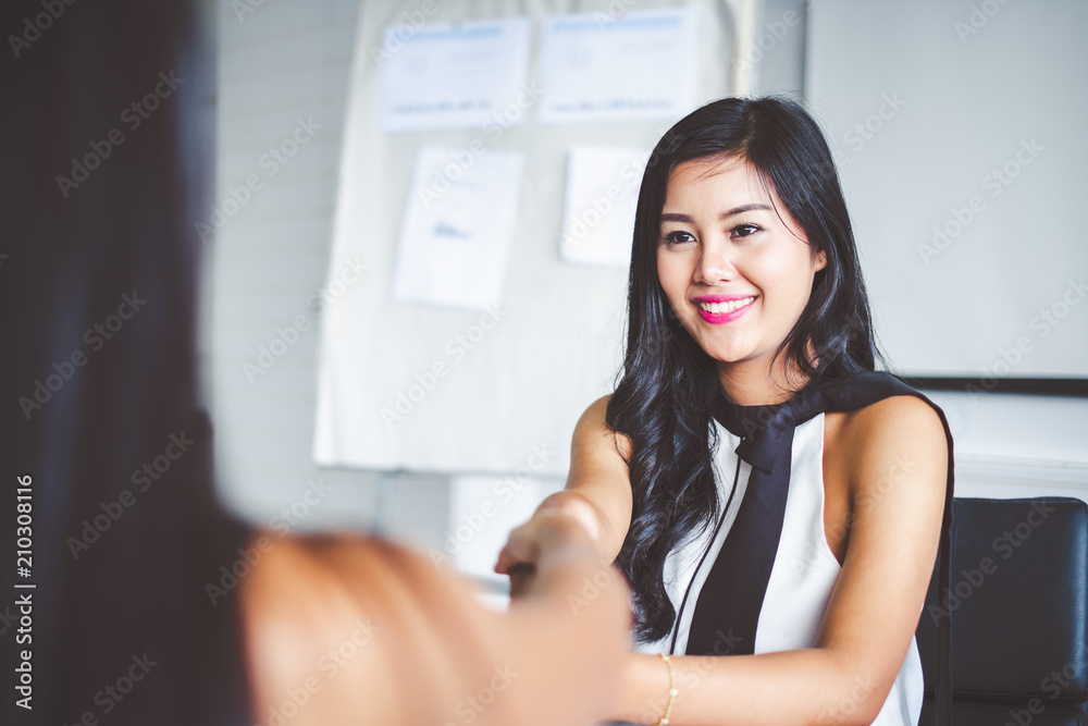 Young asian businesswoman in modern office, discussing with colleague and handshake during meeting