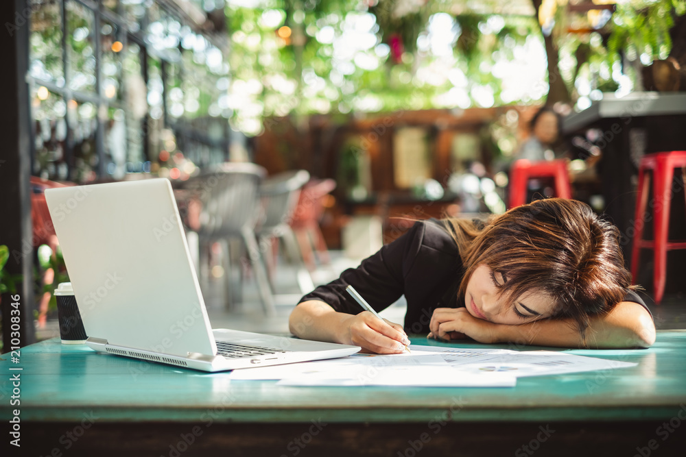 Young beautiful asian woman feeling hurt, fatigue, headache, and stressed working with laptop in cof