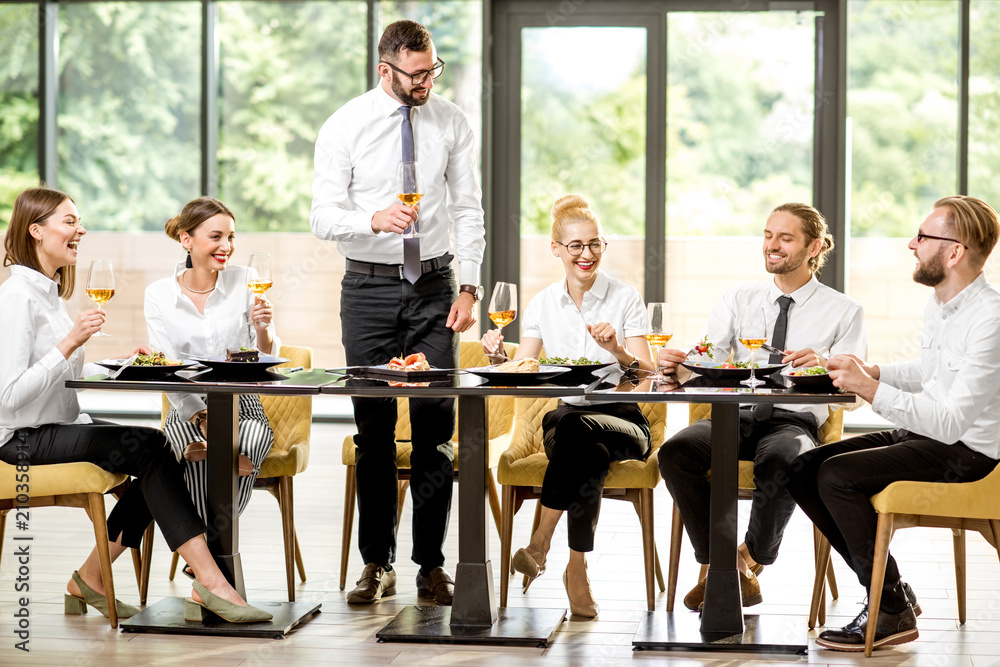 Man speaking toast during a business lunch with colleagues sitting at the spacious restaurant with b