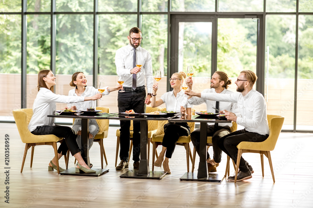 Man speaking toast during a business lunch with colleagues sitting at the spacious restaurant with b