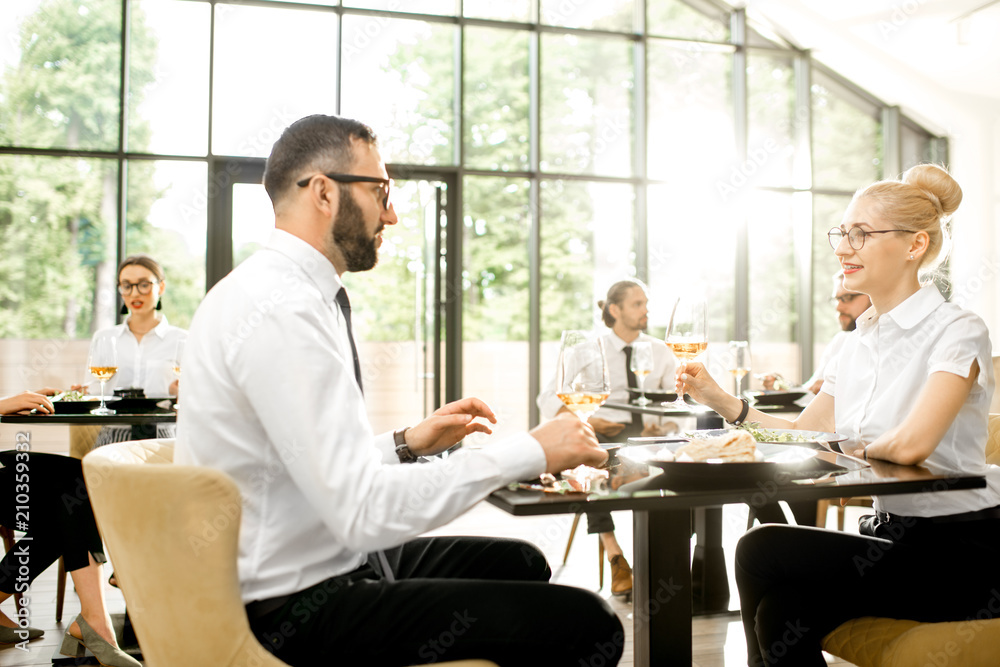 Business people having lunch with delicious meals sitting in pairs at the modern restaurant