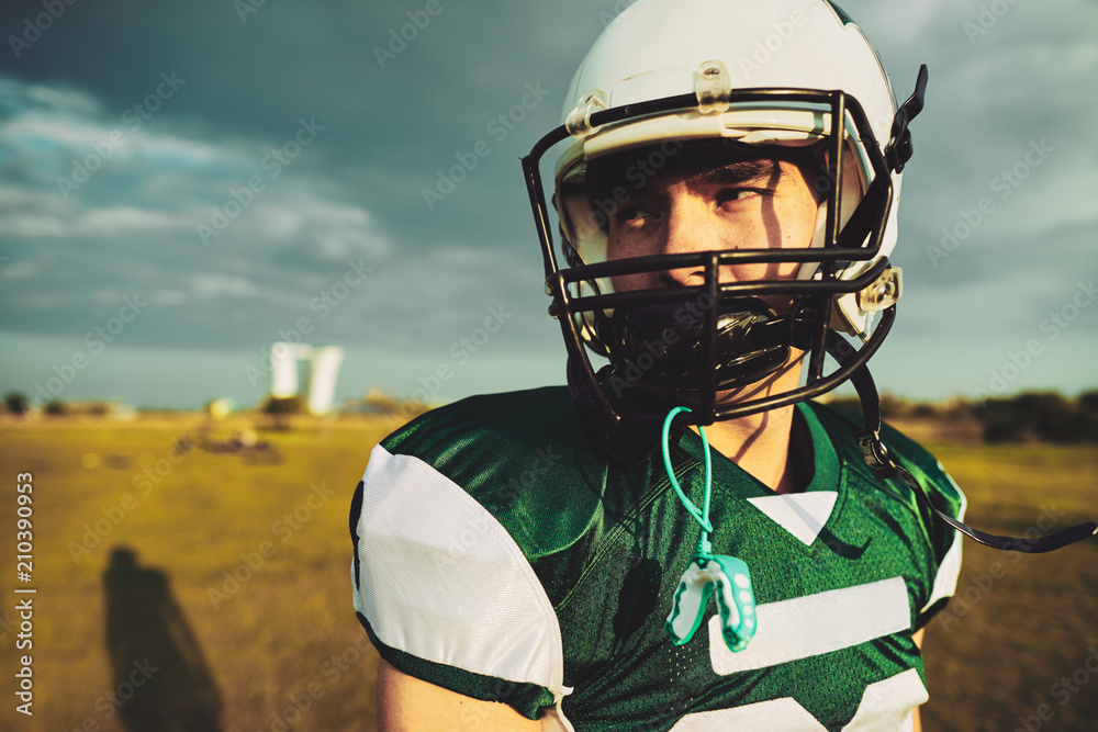 Young American football player standing alone on a field