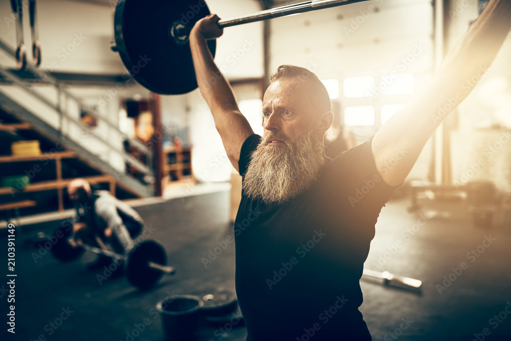 Fit mature man holding heavy weights over his head