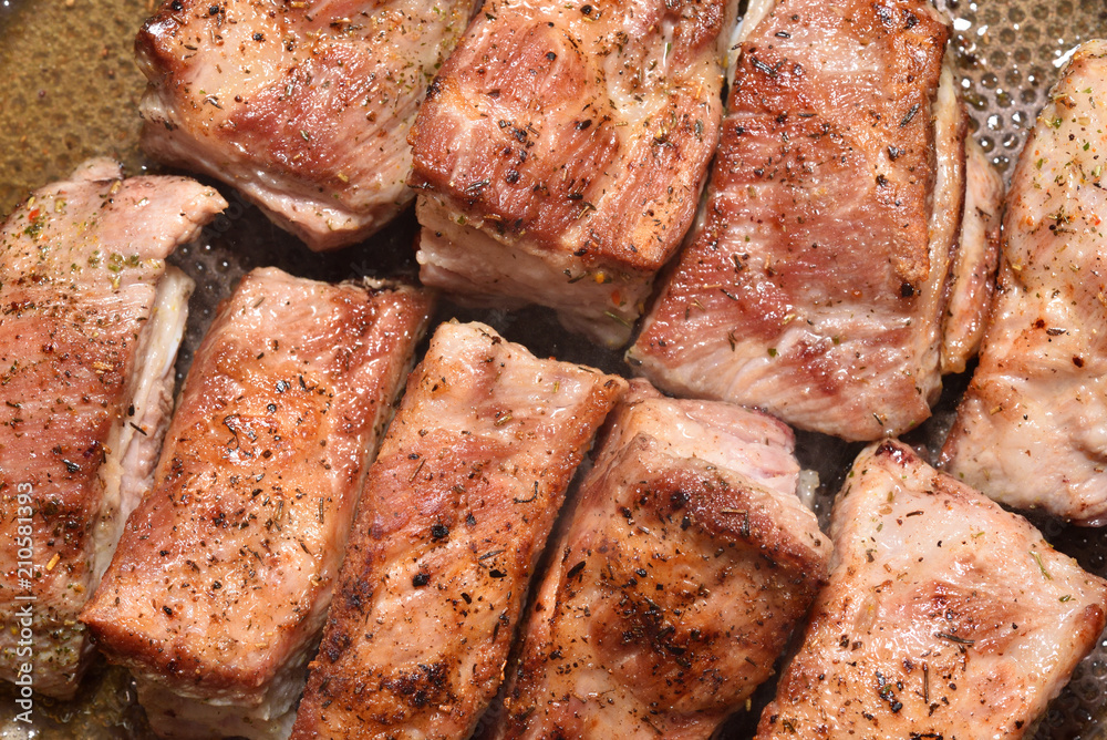 Beautiful and ruddy pork ribs are fried in a frying pan. Close-up