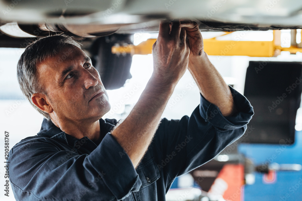 Auto mechanic fixing a car in service station