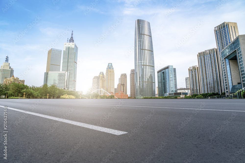 The empty asphalt road is built along modern commercial buildings in Chinas cities.