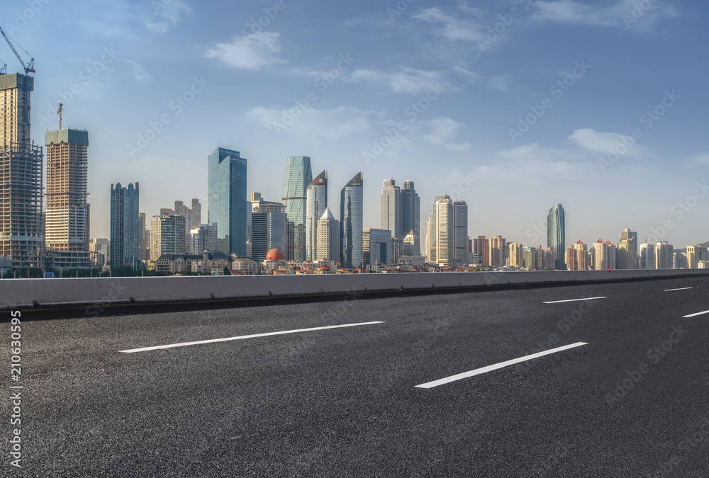 The empty asphalt road is built along modern commercial buildings in Chinas cities.