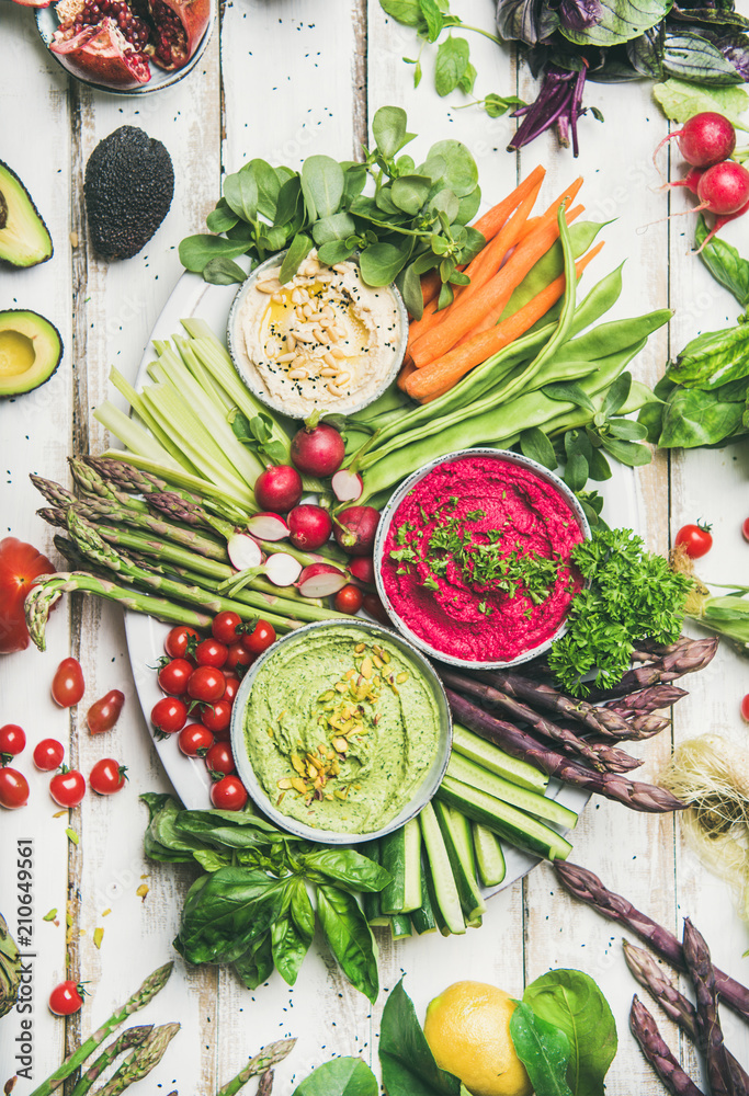 Healthy raw summer vegan snack plate. Flat-lay of chickpea, beetroot, spinach hummus dips with color