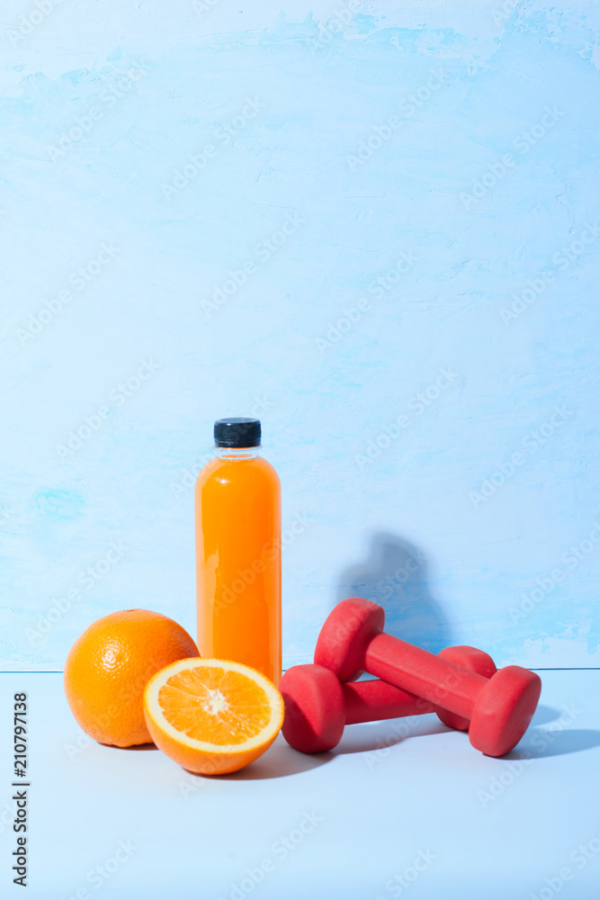 Fresh natural orange juice with dumbbells on table. Healthy drink.