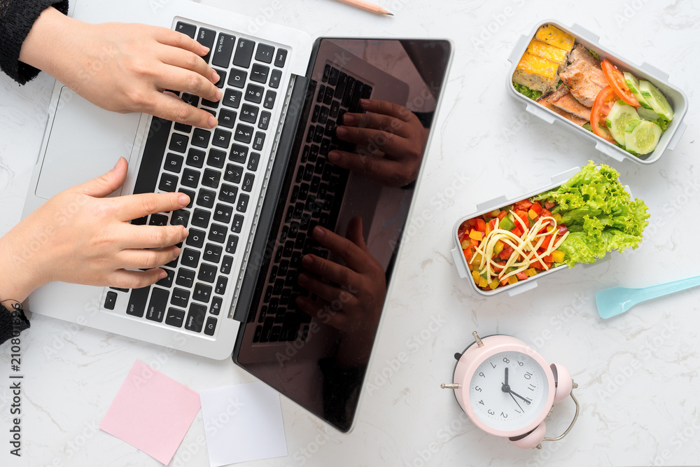 Businesswoman eating organic vegan meals from take away lunch box at  working table with laptop