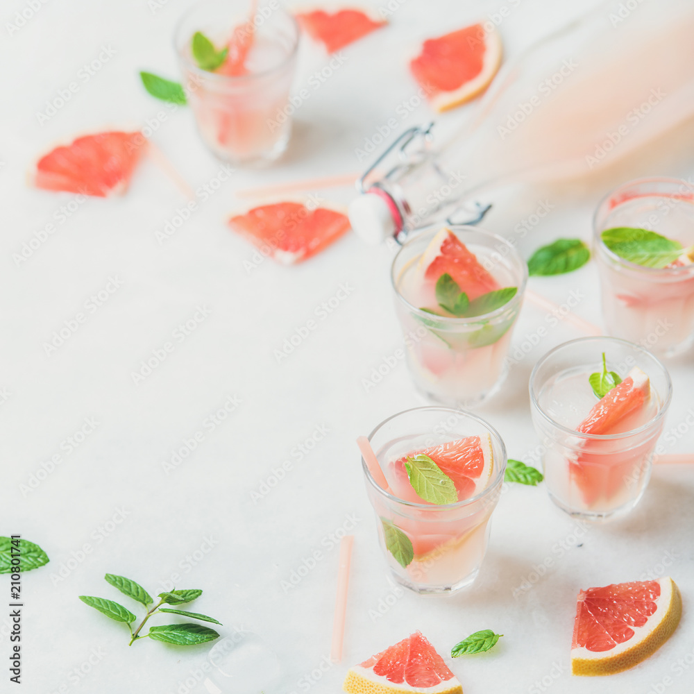 Flat-lay of cold refreshing summer alcohol cocktail with fresh grapefruit, mint and ice in glasses o