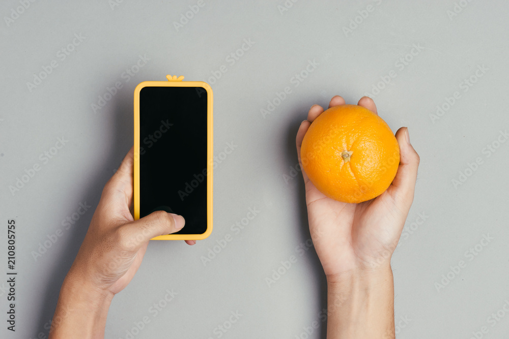 Male hand holding a smartphone against fresh oranges