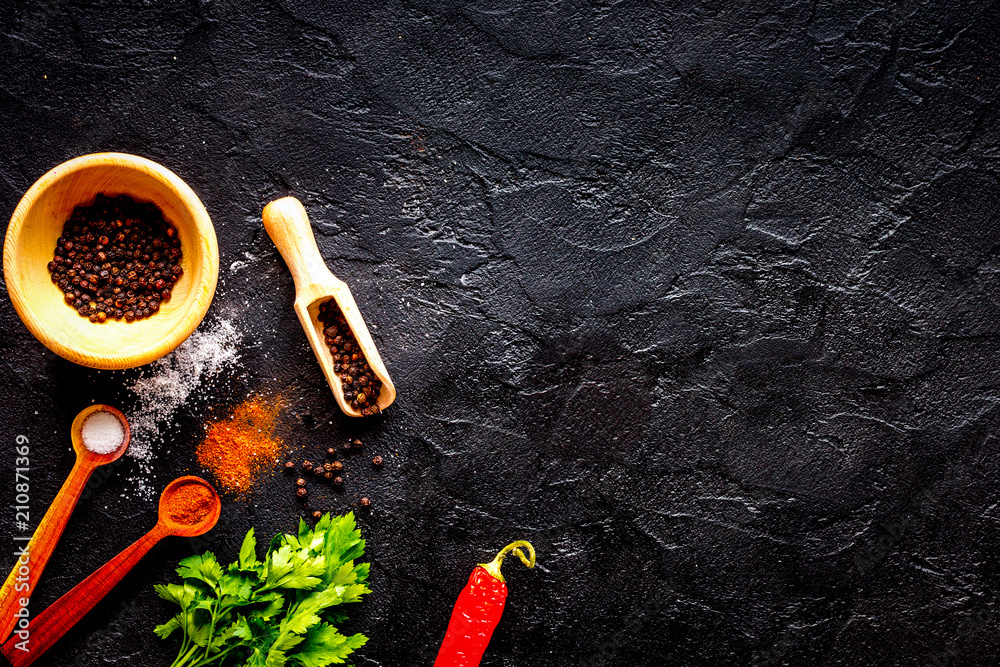 spices in wooden spoon on dark background top view