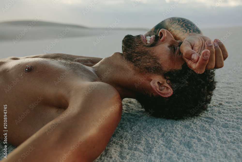 Tired man resting on sand after intense workout