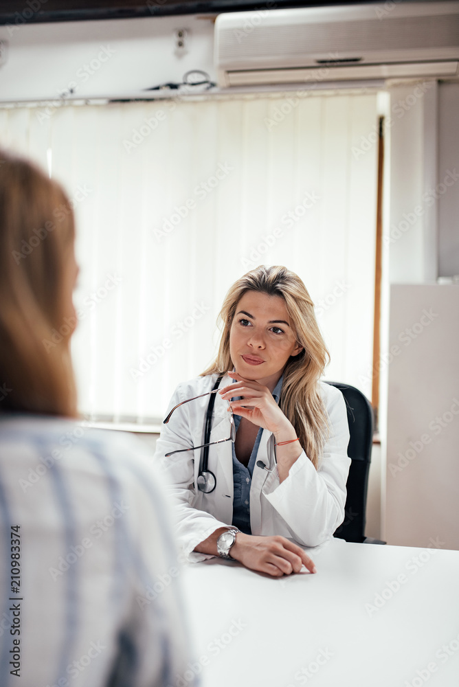 优雅的女医生在办公室里听病人说话。