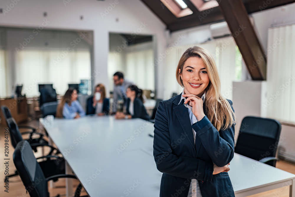 Portrait of a business woman with a team in meeting in background.