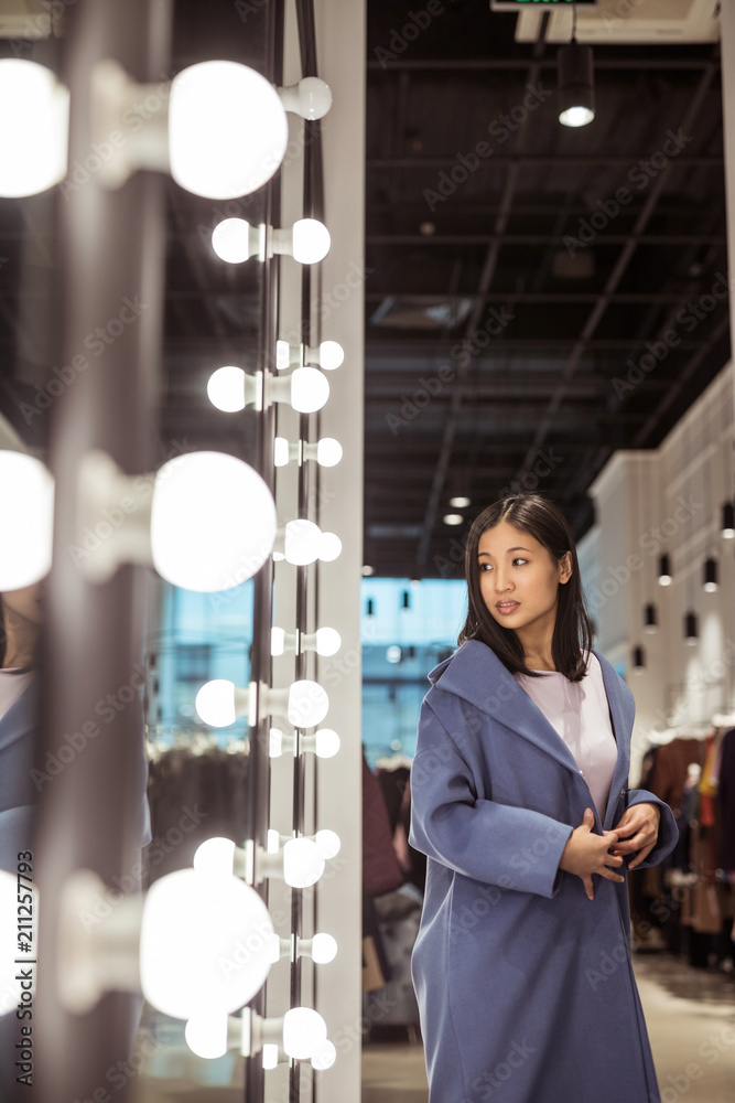 Young woman in a coat at the mirror