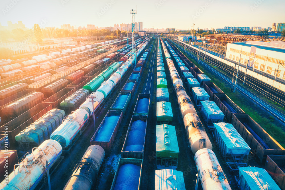 Aerial view of colorful freight trains at sunset. Cargo wagons with goods on railway station. Railro