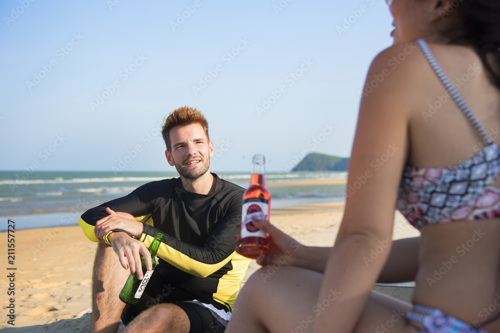 情侣在海滩上喝啤酒放松