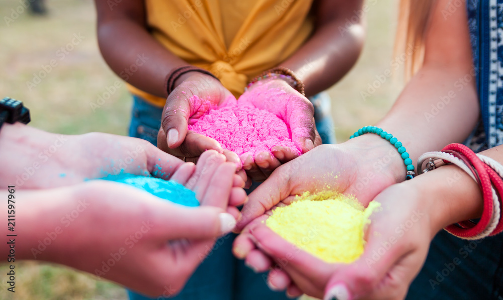 Multiethnic group of friends holding colorful powder in hands at holi festival