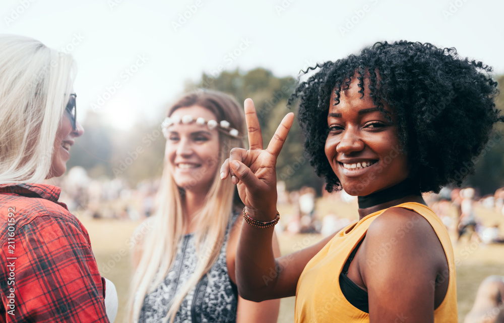 朋友们在夏天一起在户外玩得很开心，美丽的黑人女孩微笑着做着和平的手势