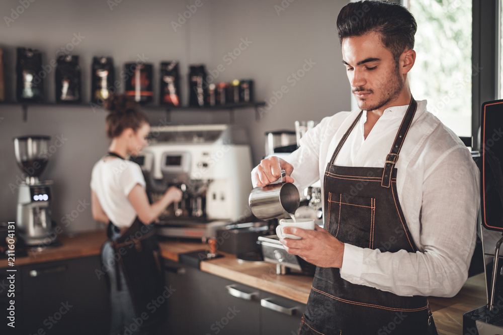 Professional barista pouring milk make coffee latte art