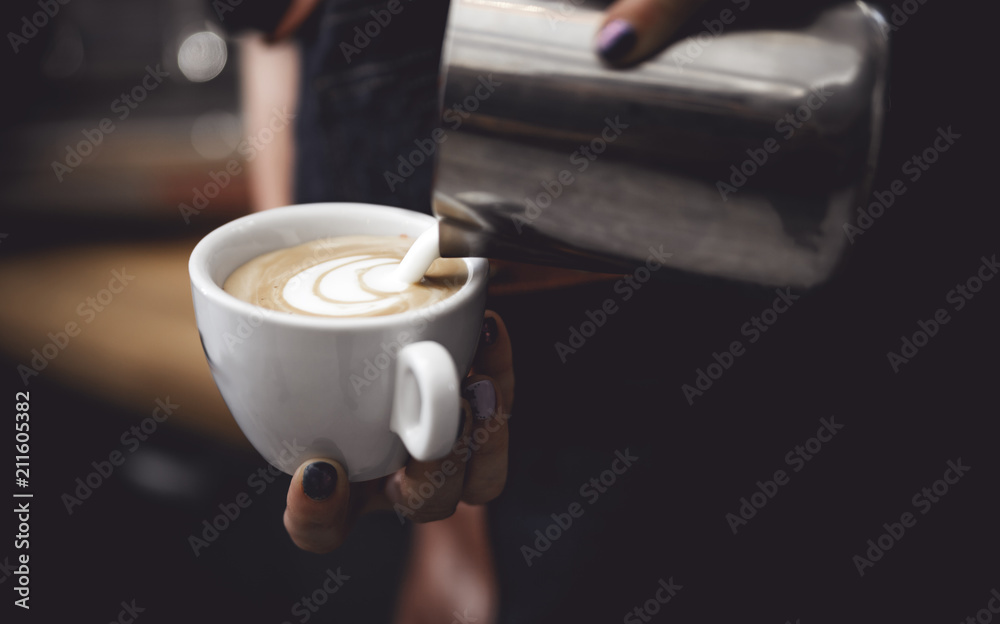 Coffee latte art, barista pouring milk into cup