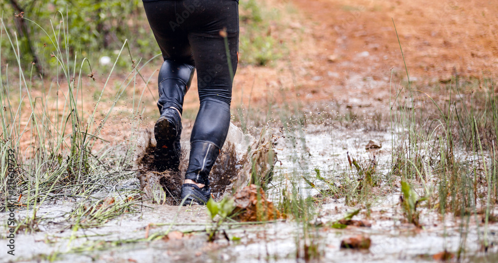 Running through dirty puddle splashing mud, cross country trail