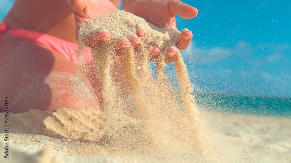 CLOSE UP: Unrecognizable woman in bikini picks up a handful of hot white sand.