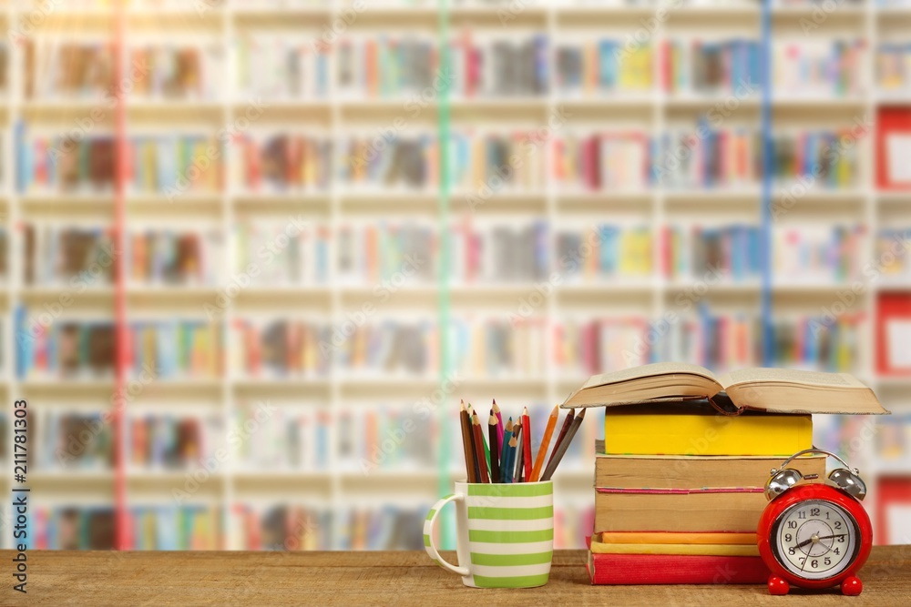 Composite image of stack of books by mug with colored pencils