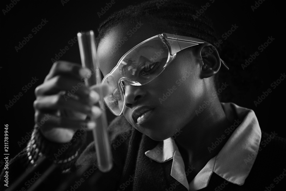 Schoolgirl doing a chemical experiment against black background