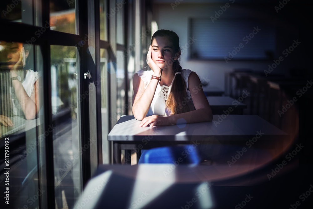 Thoughtful schoolgirl sitting in classroom