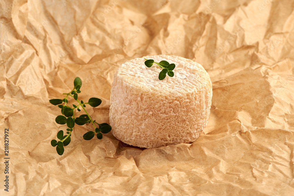 Crottin cheese with thyme leaves on brown package paper.