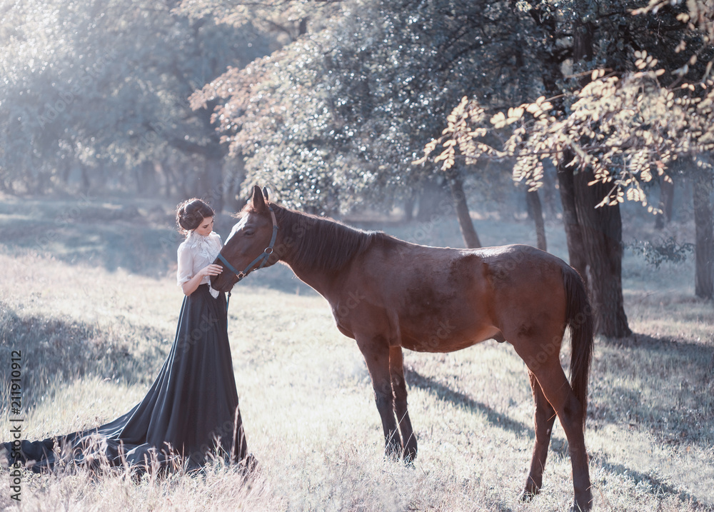 A young princess in a vintage dress with a long train, with tenderness and love, hugs her horse. The