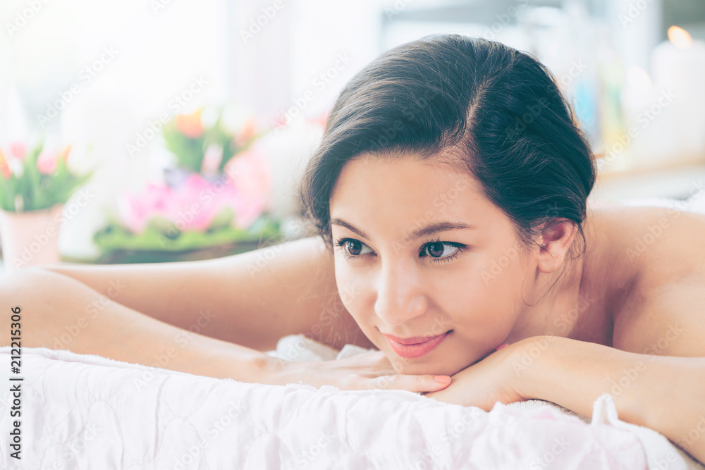 Relaxed young woman lying on spa bed for massage.