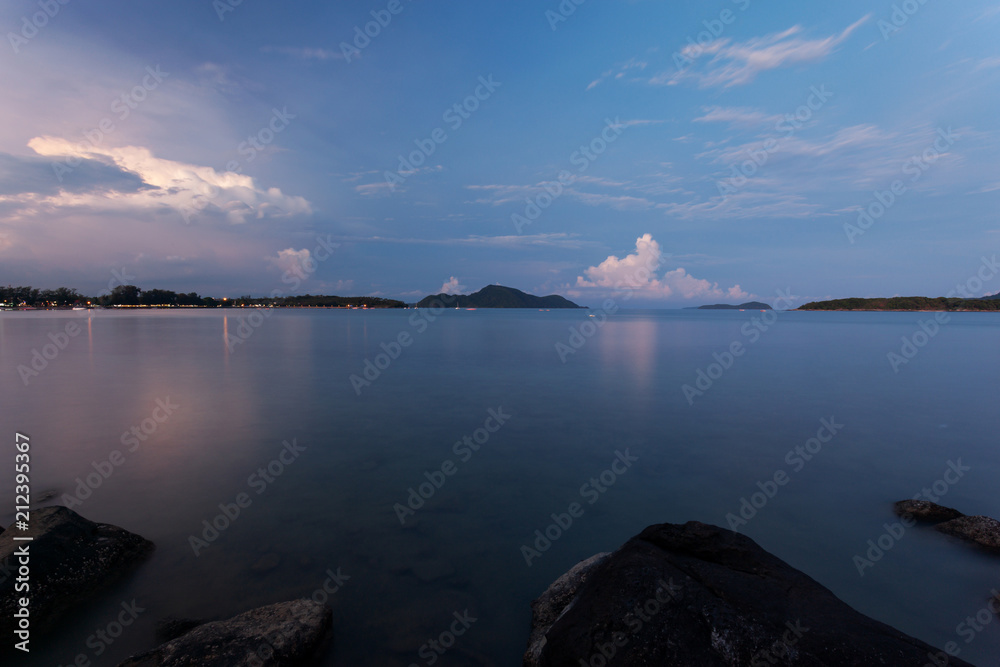 戏剧性的天空和波浪海景的长曝光图像，日落景色背景中有岩石，很美