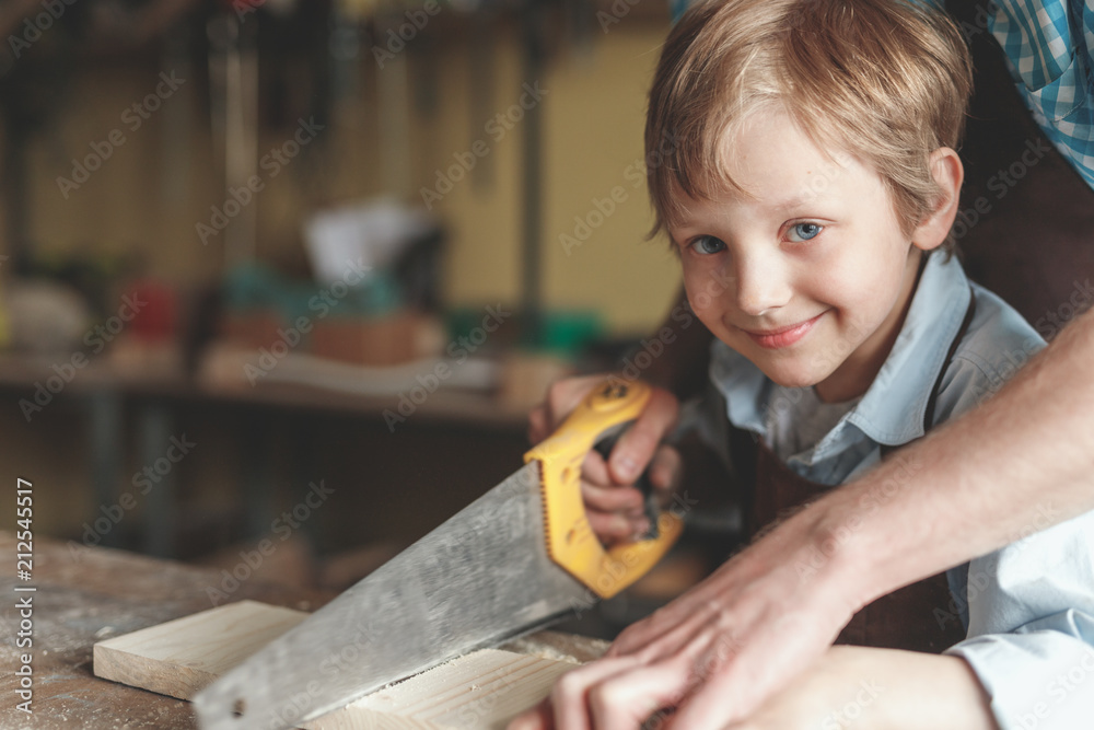 Father and a little son sawing a board